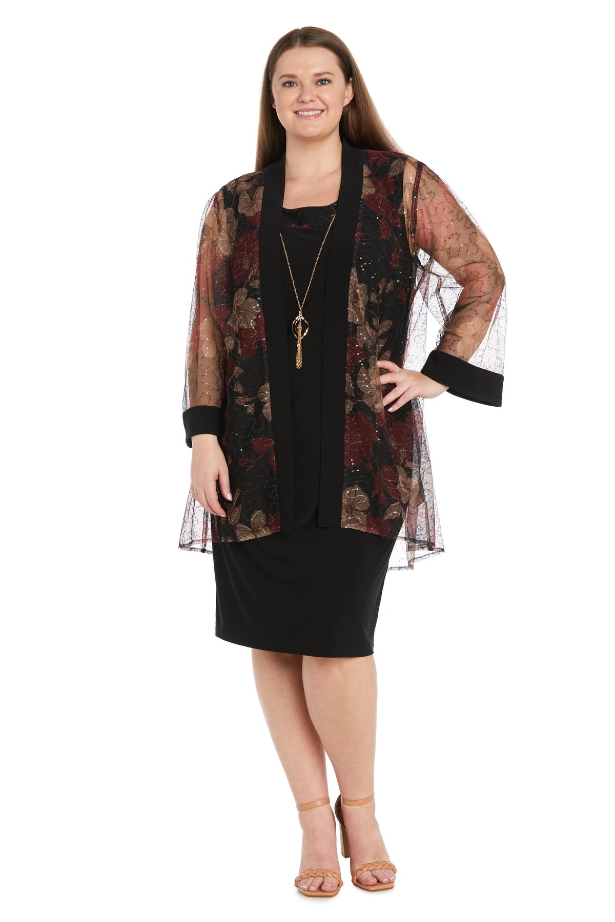 Woman wearing the Plus-Size Jacket Party Dress: R&M Richards 3312W—a semi-formal dress with a sheer floral kimono-style jacket—paired with a long necklace and beige sandals, smiling against a white background.